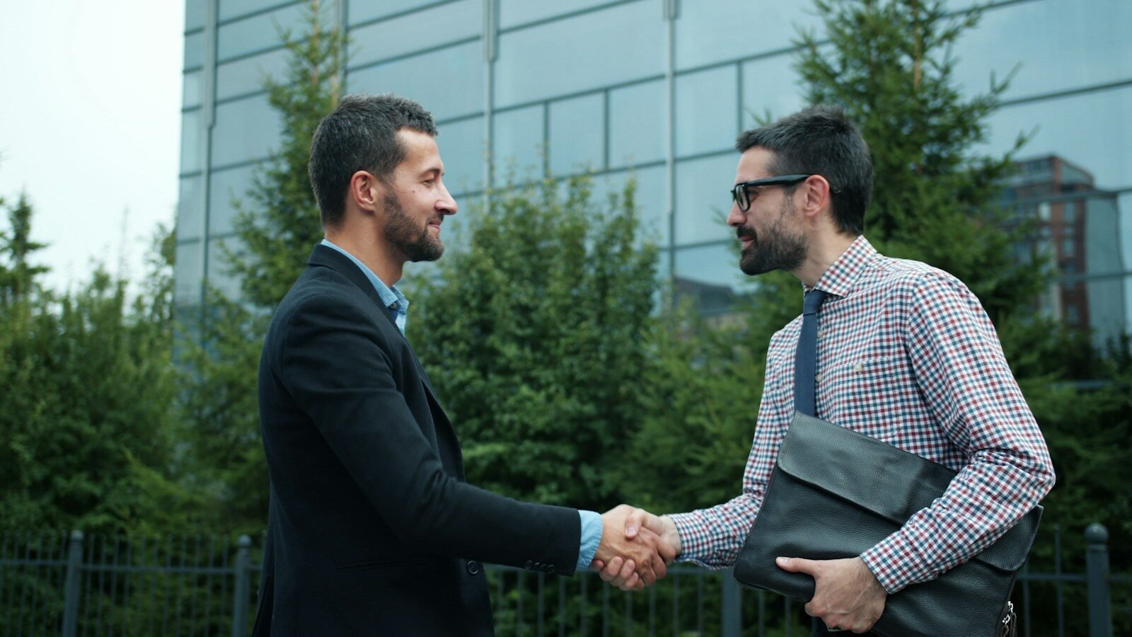 Photo by Vitaly Gariev Two businessmen shaking hands outside modern building