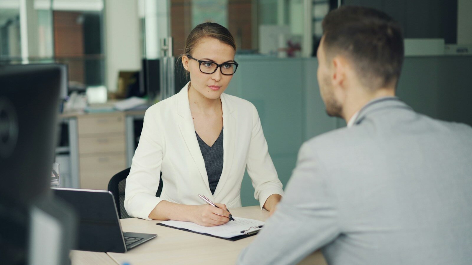 Photo by Vitaly Gariev Woman in glasses interviews man at office desk