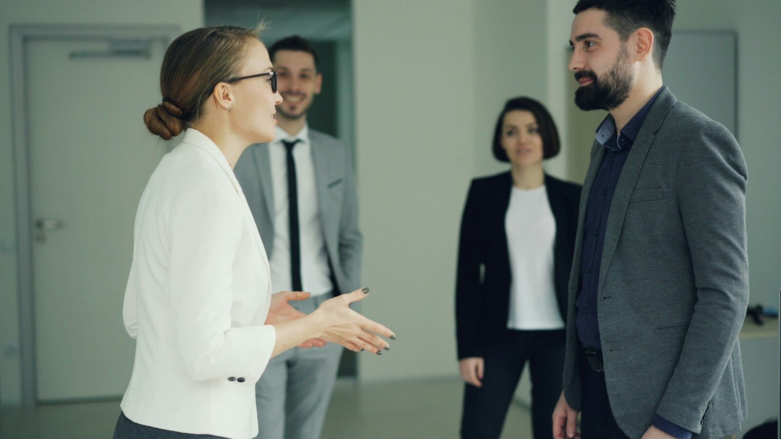 Two business people conversing, others observing