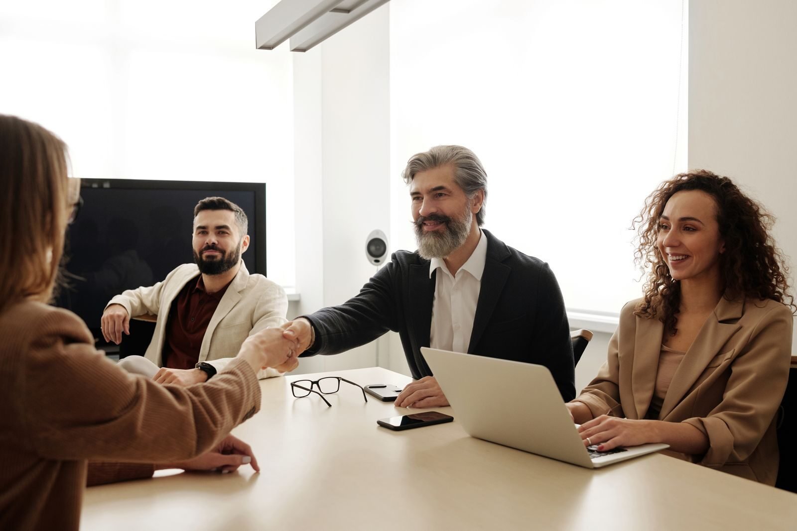 Photo by Edmond Dantès A group of business professionals shake hands during a meeting in a modern office setting.