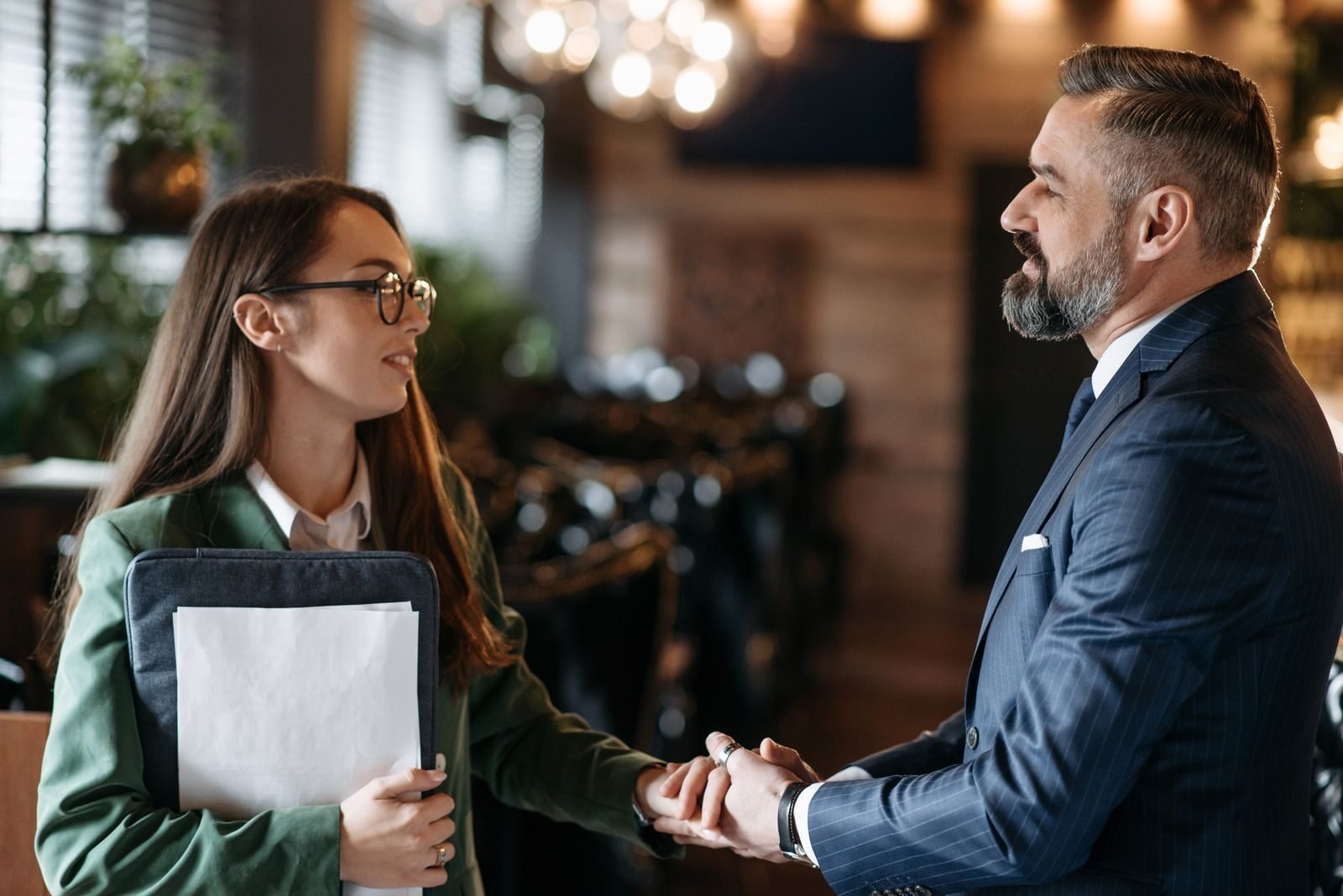 Photo by Pavel Danilyuk A man and woman shaking hands during a business meeting in a modern office setting.